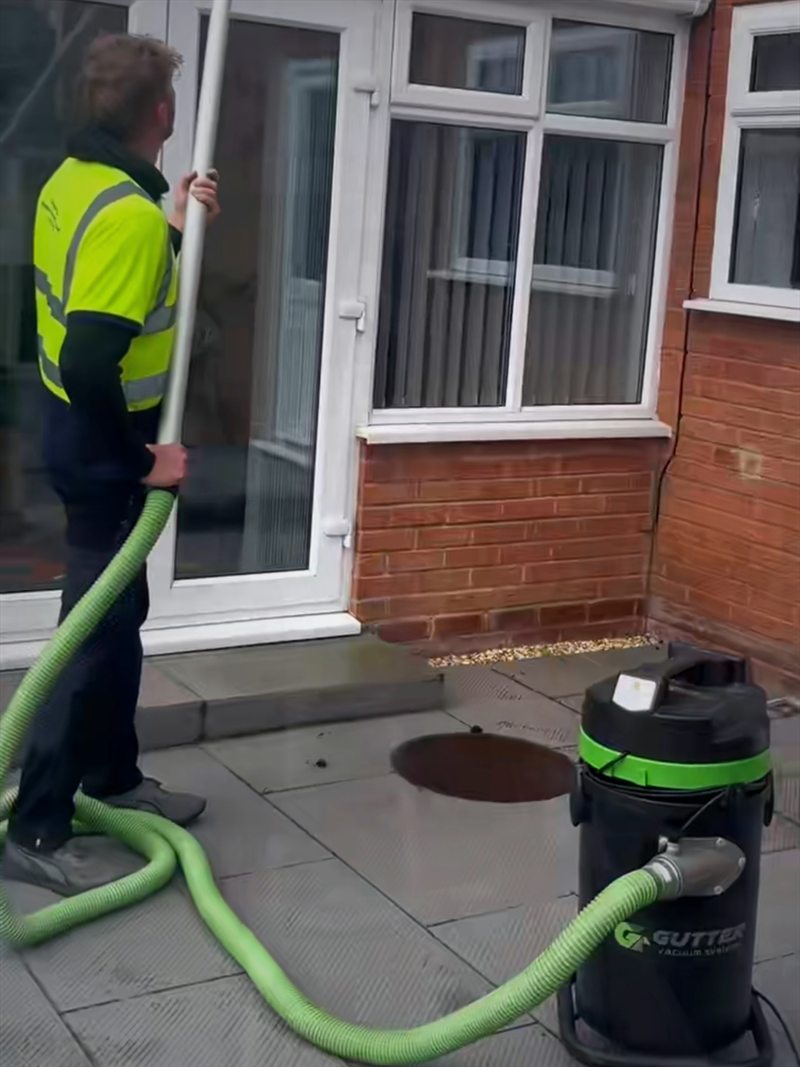 Gutter-vacuum unit on a patio with high-reach poles clearing a gutter from ground level