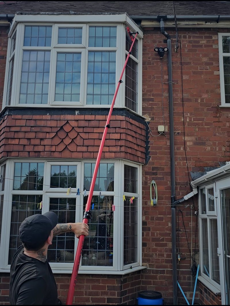 Ben cleaning upstairs bay windows from ground level with an extended water-fed pole