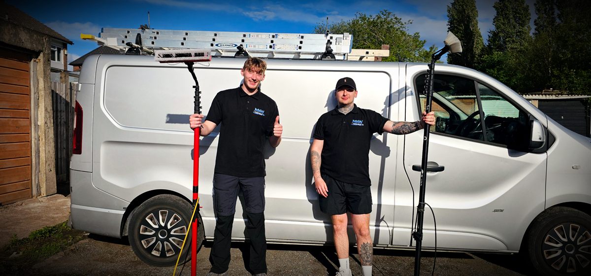 Two Morgan & Walker cleaners in branded polo shirts standing either side of the company van, each holding a water-fed pole