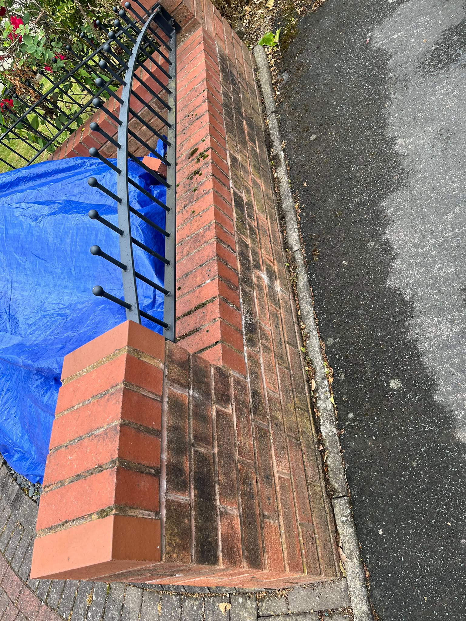 Dirty brick garden wall and pier, heavily stained with black algae, before pressure washing