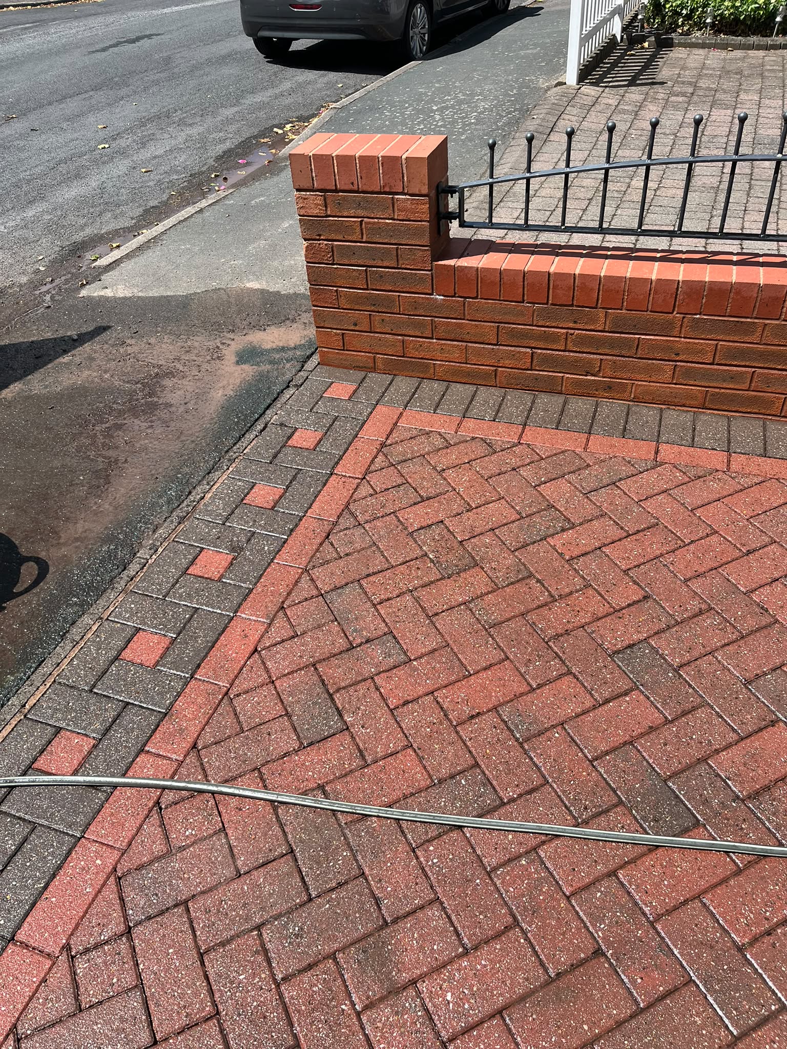 Clean red block-paving driveway after pressure washing, viewed from the street