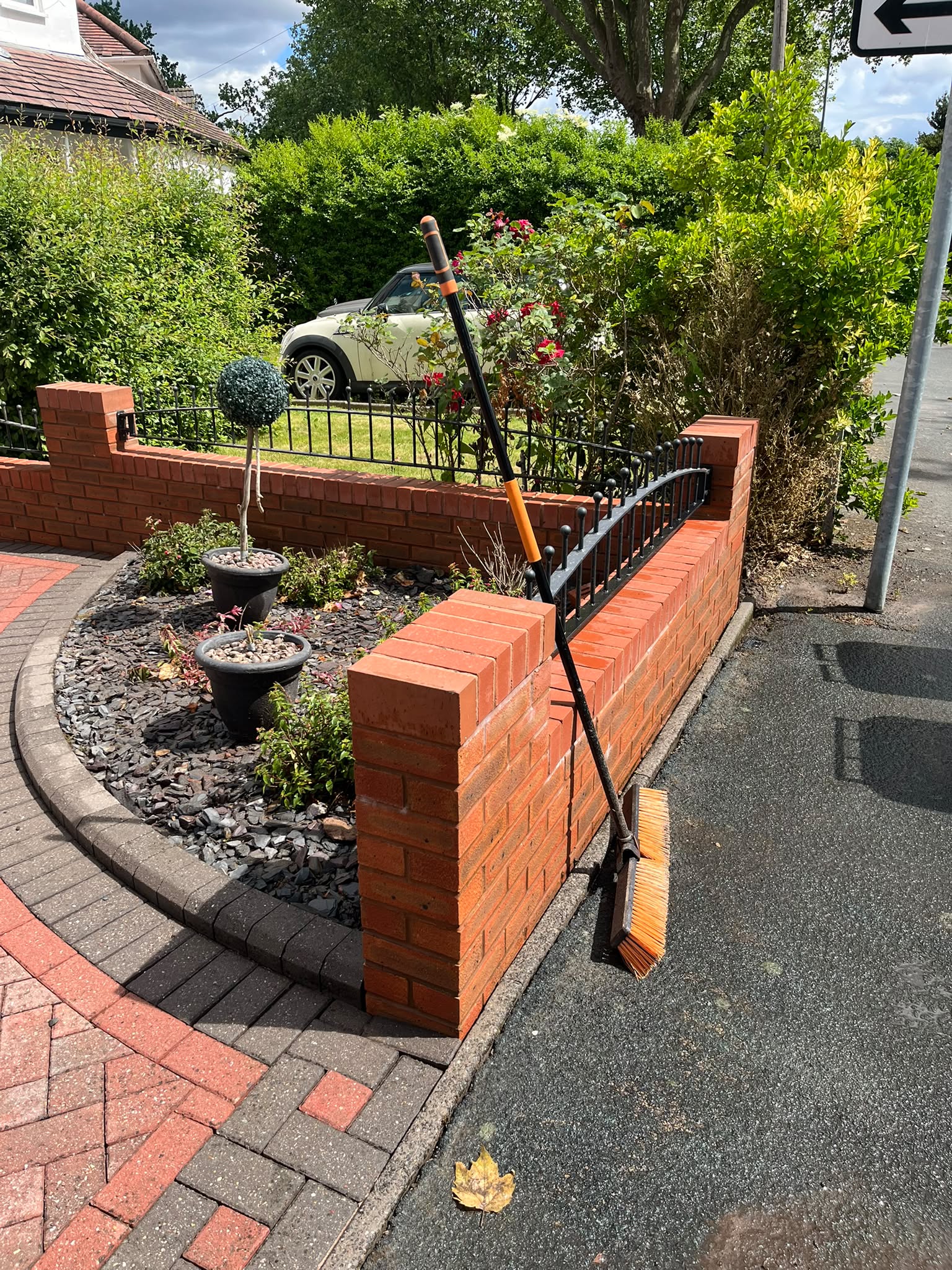 Broom leaning against a clean brick garden wall after pressure washing