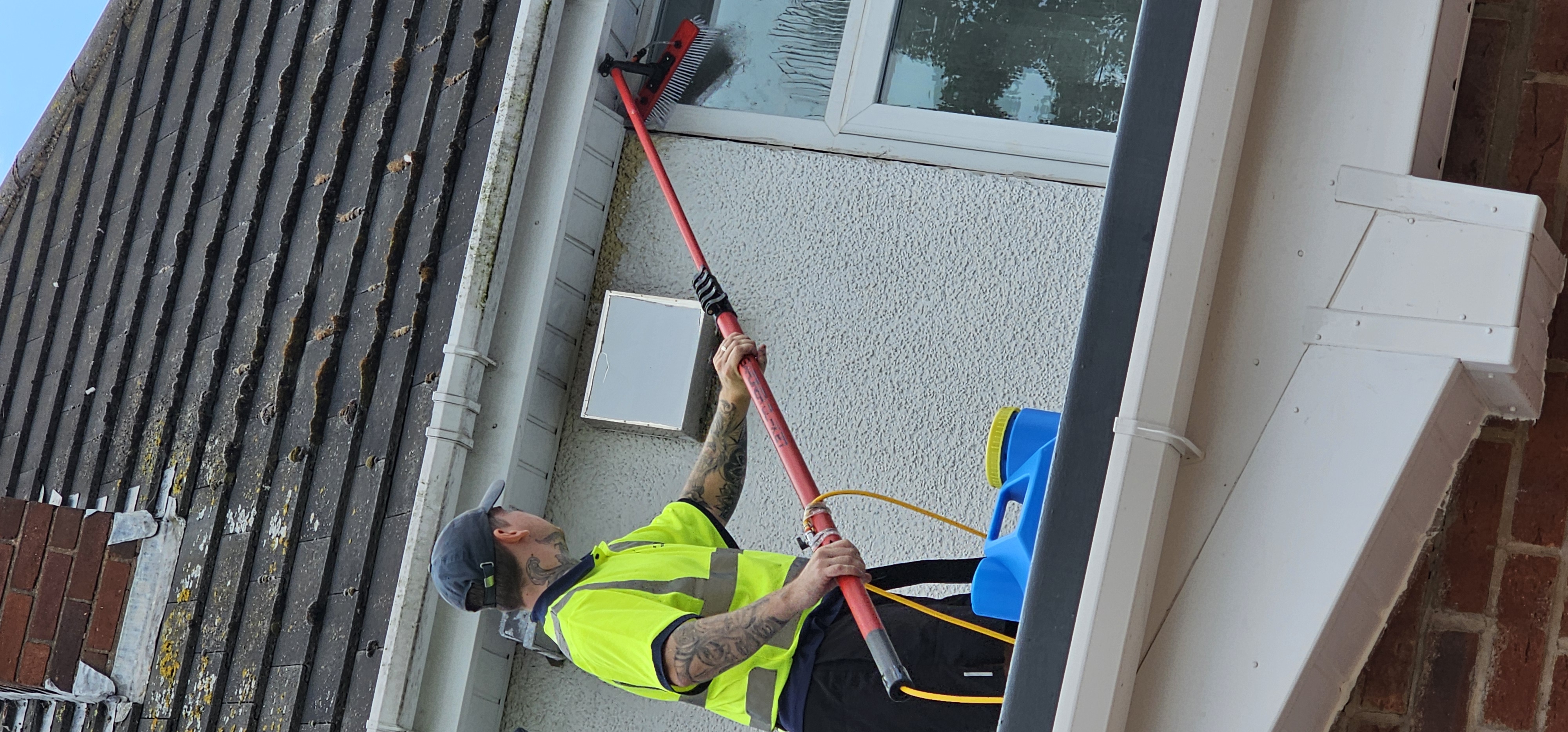 Morgan & Walker technician cleaning upstairs bay windows with a water-fed pole